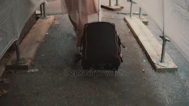 Fille réfugiée voyageuse avec sac à dos et valise traversant le couloir de construction blanc. Réparation de rue . — Video