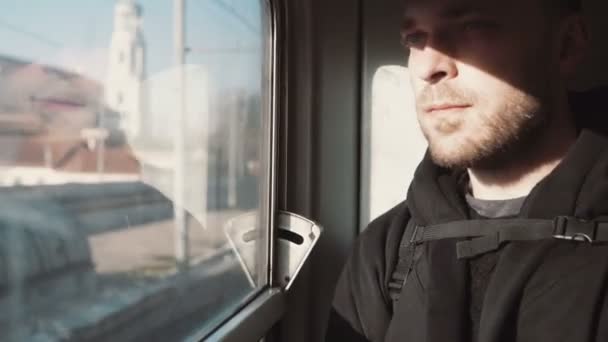 Bel giovanotto che viaggia in treno. Attraente maschio guardando la finestra e pensando, seduto all'ombra . — Video Stock