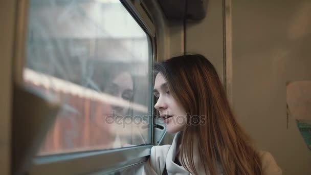 Νεαρή όμορφη γυναίκα που ταξιδεύουν με το τρένο. Ελκυστική κοπέλα ψάχνει στο παράθυρο και να εξερευνήσετε το τοπίο έξω από. — Αρχείο Βίντεο