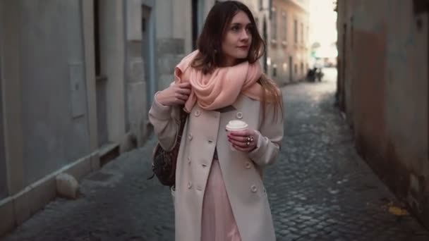 Portrait of young stylish woman walking in the city centre. Happy girl explores the old streets and drinking coffee. — Stock Video