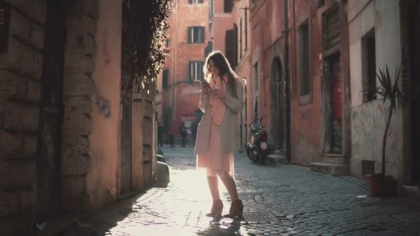 Portret kobiety Brunetki stojąc w małą uliczkę i przy użyciu technologii ekranu dotykowego smartfona. — Wideo stockowe