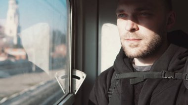 Trenle seyahat yakışıklı delikanlı. Çekici erkek penceresine bakarak ve düşünme, gölgesinde otururken.