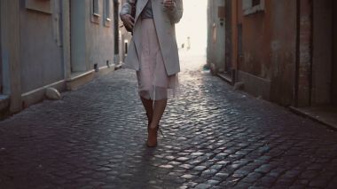 Yakın çekim görünümünü de güneşli bahar ilçesinde Avrupa'da sokak yürüyen genç kadın. Şık kız yalnız eski şehir keşfetmek.
