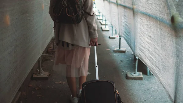 Ragazza in viaggio con zaino e valigia che cammina attraverso il corridoio di costruzione. Giovane donna che si trasferisce nel nuovo appartamento . — Foto Stock