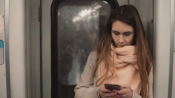 Retrato da jovem mulher bonita de pé no metrô. Menina usa smartphone, navegar na Internet em trem de metrô — Fotografia de Stock