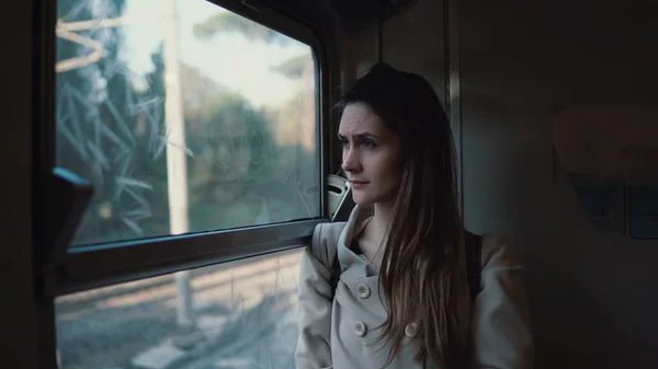 Молодая брюнетка путешествует поездом. Привлекательная девушка смотрит в окно в пейзаж снаружи, делает прическу . — стоковое фото