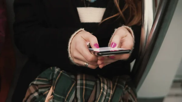 Vista de perto da mão da mulher segurando um smartphone, sentado no transporte público. Menina usa tecnologia touchscreen . — Fotografia de Stock