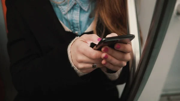 Vista de perto da mão da mulher segurando um smartphone, sentado em transportes públicos. Menina navegar na Internet com touchscreen . — Fotografia de Stock
