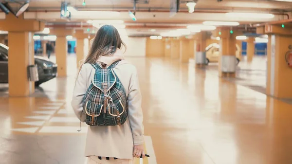 Joven viajero femenino elegante caminando a través del aparcamiento del aeropuerto con la maleta. Chica ven de vacaciones . — Foto de Stock