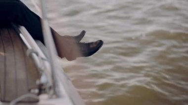 Yakın çekim adam bacaklar dışında yat daha düşük bir bakış. İşadamı sailboard yalnız doğada bir dinlenme--dan iş var.