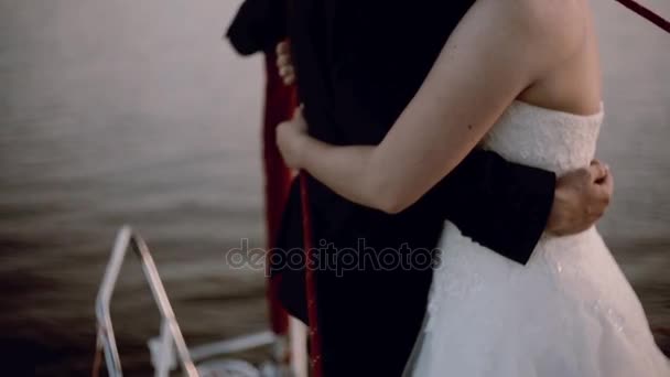 Vista de cerca de la novia pareja y el novio abrazándose en la parte nasal del yate. Ceremonia de boda en el barco — Vídeos de Stock