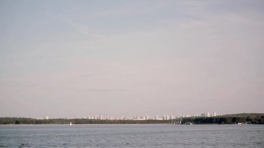 Hareketli gemiden şehir yatay olarak görüntüleyin. Parlak güneşli açık suda, göl manzara mavi su ile.