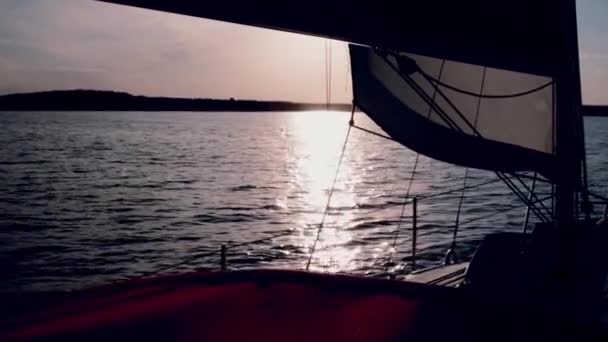Όμορφο σκάφος που κινείται μέσα από τη θάλασσα στο ηλιοβασίλεμα. Sailboard περνά μέσα από τα κύματα στη λίμνη με πλήρη ταχύτητα στο βράδυ. — Αρχείο Βίντεο