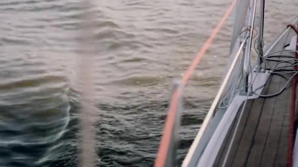 Seite des Segelbootes fährt mit voller Geschwindigkeit durch das Meer. Jachtsegeln im Wind an sonnigen Tagen. Nahaufnahme. — Stockvideo