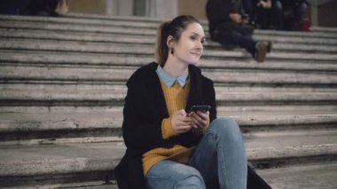 Merdiven akşam ve arayan birisi için oturan öğrenci kız gülümse. Kadın smartphone kullanmak, kaş belgili tanımlık enterne.