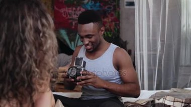Sabah yatakta çok ırklı çift. Yaşlı photocamera genç yakışıklı adam alarak fotoğrafları, kadın poz.