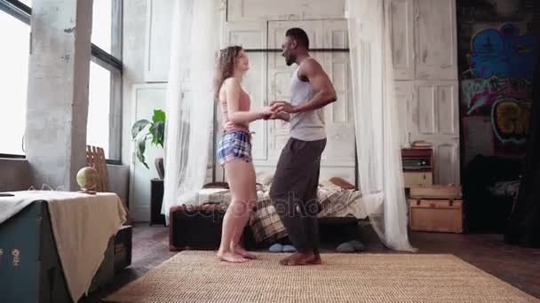 Jeune couple multiracial dansant le matin dans un appartement lumineux. L'homme africain et la femme européenne s'amusent ensemble . — Video