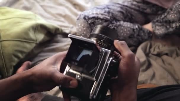 Der Mann fotografiert die Frau mit einer alten Bewegtbild-Fotokamera auf dem Bett. Ansicht der Frau im Videorecorder. — Stockvideo