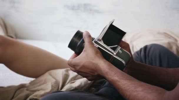 Vista de cerca del fotógrafo tomando fotos en una vieja cámara de película en movimiento. Mujer joven en pijama posando al hombre . — Vídeos de Stock