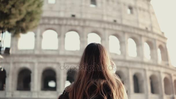 Young brunette tourist exploring the Colosseum in Rome, Italy. Woman takes the photo of sight, uses smartphone. — Stock Video