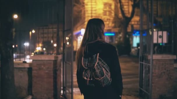 Achteraanzicht van jonge brunette vrouw lopen laat 's nachts in het centrum van de stad Rome, Italië. Meisje draait en zie het Colosseum. — Stockvideo