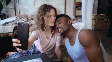Mutlu çok ırklı iki Smartphone'da selfie fotoğraf çekmek. Kadın ve erkekte pijama yapmak komik surat, seyir iyi eğlenceler.