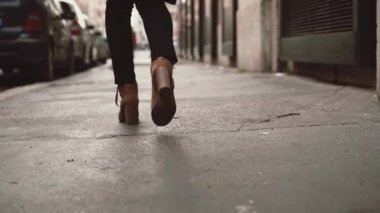 Küçük sokakta yürüyen şık kadın görmek. Topuklu ayakkabı giyen kız şehrin içinden gidiyor. Ağır çekim.