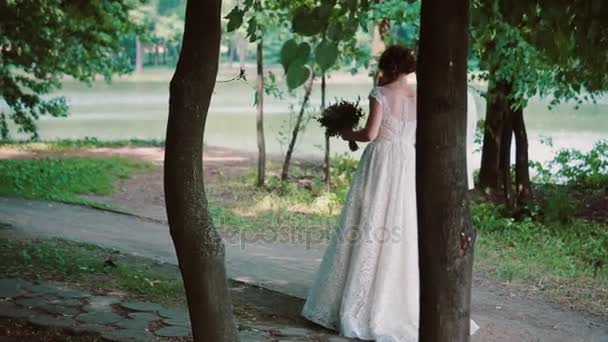 아름 다운 부부 사랑에 그들의 결혼식 날, 숲, 포옹, 화창한 여름 날을 즐기고 산책을 공유 합니다. Steadicam 샷 — 비디오