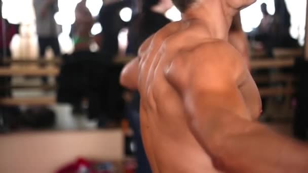 Bir erkek vücut geliştirmeci direniş band ile egzersiz yaparak çıplak gövde ile yan — Stok video