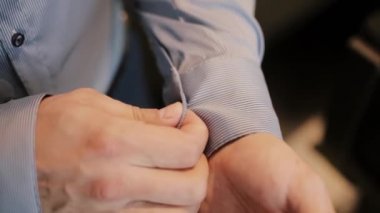 Genç işadamı sabah giyiniyor. Adam düğmeleri manşet gömlek, takım elbisesi koyarak. Erkek el görünümünü yakın çekim.