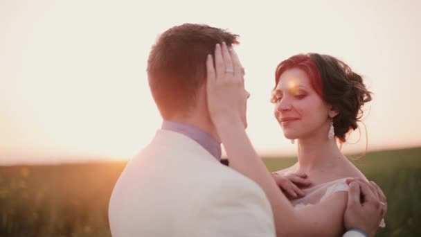 Hermosa pareja en el amor beso en la naturaleza en el día de su boda en verano. Maravillosa puesta de sol en el campo . — Vídeos de Stock