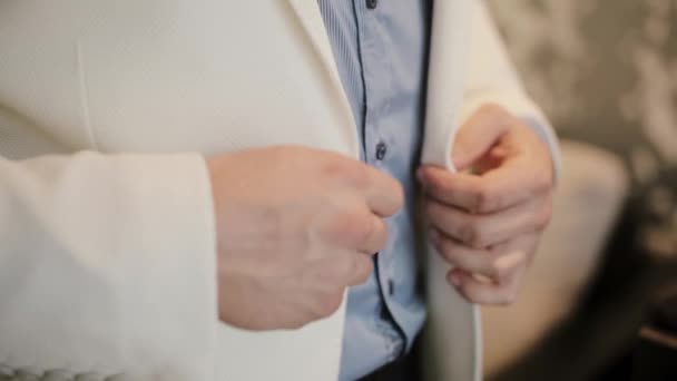 Showman preparándose para un trabajo, poniendo su traje formal. Vista de cerca de los botones de las manos masculinas una chaqueta blanca . — Vídeo de stock