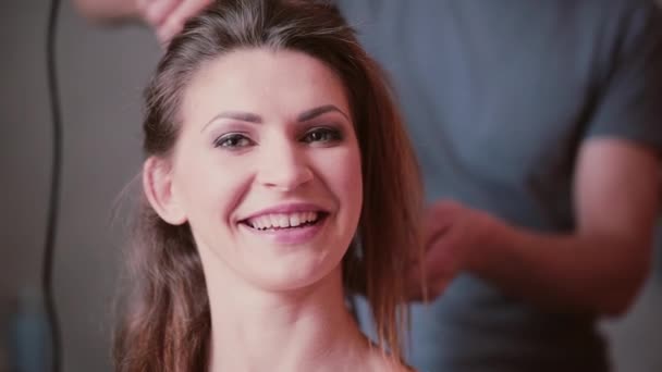 Frisören göra en ny frisyr för en flicka. Porträtt av ung attraktiv kvinna talar med någon och ler. — Stockvideo