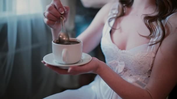 Detail pohledu mladé ženy v bílém peignoir pití kávy během kadeřník dělá nový účes. — Stock video