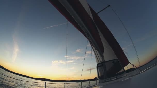 Yacht sailing in open water. Sail waves in wind, boat goes through water. Beautiful water landscape on sunset. — Stock Video