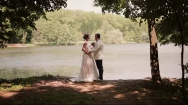 Düğün günü Lovers birbirimizi, bir nehir banka öpüşme stand. Çok güzel bir elbise içinde mutlu gelin.