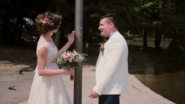 Наречений і наречена, стоячи біля серця знак сміятися. Насолоджуйтесь гарна пара день весілля в літній час. — стокове відео