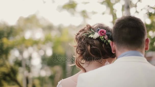Achteraanzicht van liefhebbers leunend op elkaar. Close-up van hun hoofd. Bruid met een mooie hair-do met bloemen. — Stockvideo