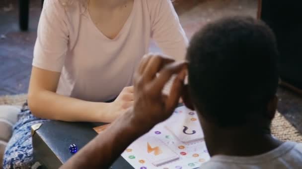 Multiraciale paar het bordspel samenspelen. Man en vrouw de taak op kaart maken en samen lachen. — Stockvideo