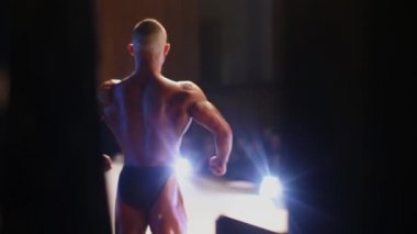 Vücut geliştirme yarışmalar. Vücut geliştirmeci seyirci önünde poz. Backview kasları gösteren bir adam