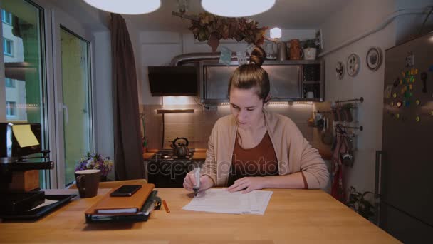 Jeune femme d'affaires avec des documents assis à la table et travaillant avec des papiers. Heures supplémentaires à la maison . — Video