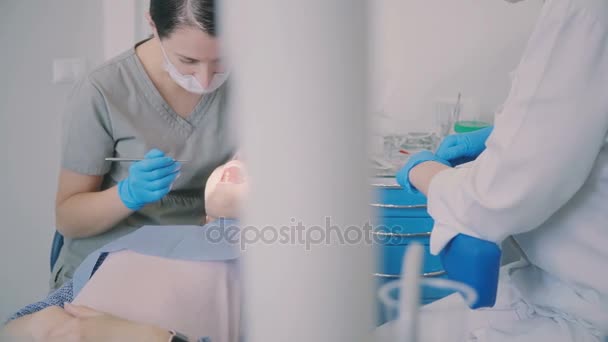 Jovem que visita o consultório do dentista. Mulher sentada na cadeira dentária enquanto o médico checa sua boca . — Vídeo de Stock