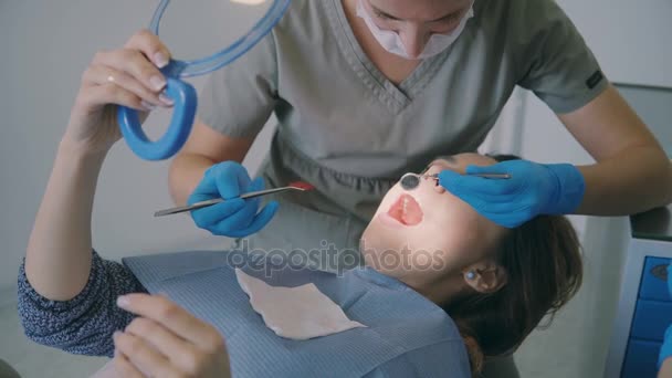 Une femme rend visite au dentiste. Femme allongée sur une chaise dentaire et tenant le miroir. Orthodontiste vérifie l'overbite . — Video