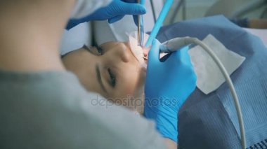 Diş sandalyede oturan genç kadın. Doktor Diş ayna ile çalışma ve motoru sondaj bir hastayı tedavi.