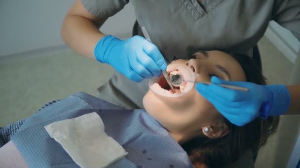 Ung kvinna besöker tandläkarens. Kvinna liggande i stolen, Doktor polering och rengöring av tänderna. — Stockvideo