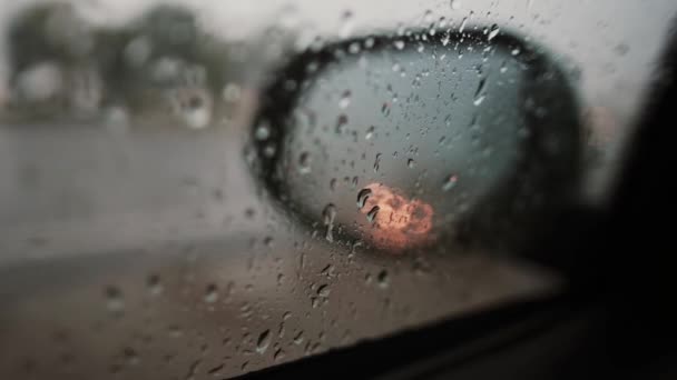 Regendruppels en reflectie van de verlichting op een spiegel van de kant van een auto. — Stockvideo