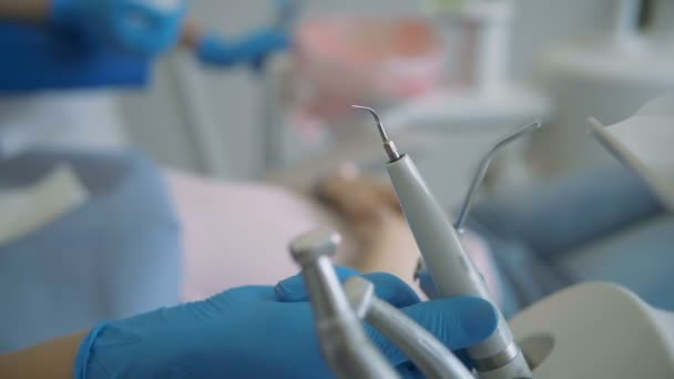 Vista de perto dos instrumentos dentários. Uma mulher a visitar a clínica, deitada na cadeira dentária. Doutor verificando-se os dentes . — Vídeo de Stock
