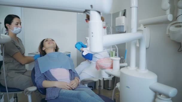 医師、歯科治療の開始は、歯科用の椅子を下げます。歯医者は口開いている女性、ランプを点灯します。. — ストック動画