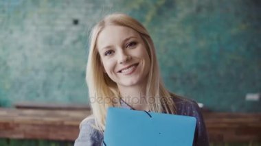 Kameraya bakarak ve modern ofiste gülümseyen genç Beyaz sarışın kadın portresi. İş yerinde başarılı çalışan.