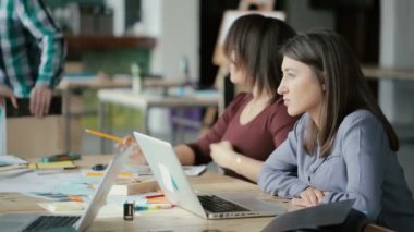 Yaratıcı KOBİ ekibi Office coworking çalışıyor. İki kadın konuşmak, fikir tartışıyor ve dizüstü bilgisayar kullanarak.